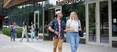 Two students walk and chat outside of the Limberlost Place entrance