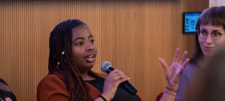 A woman with a microphone addresses an unseen audience