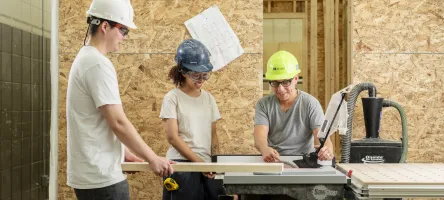 Students in a George Brown Polytechnic carpentry lab using a table saw and measuring wood during hands-on training
