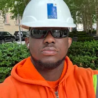 Uzoma, an Augmented Education grad wears a white hard hat, glasses, and a high vis hoody